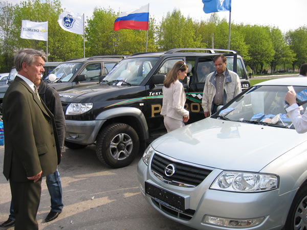 Народ привлекает серебристый Ниссан, стоящий рядом с УАЗами